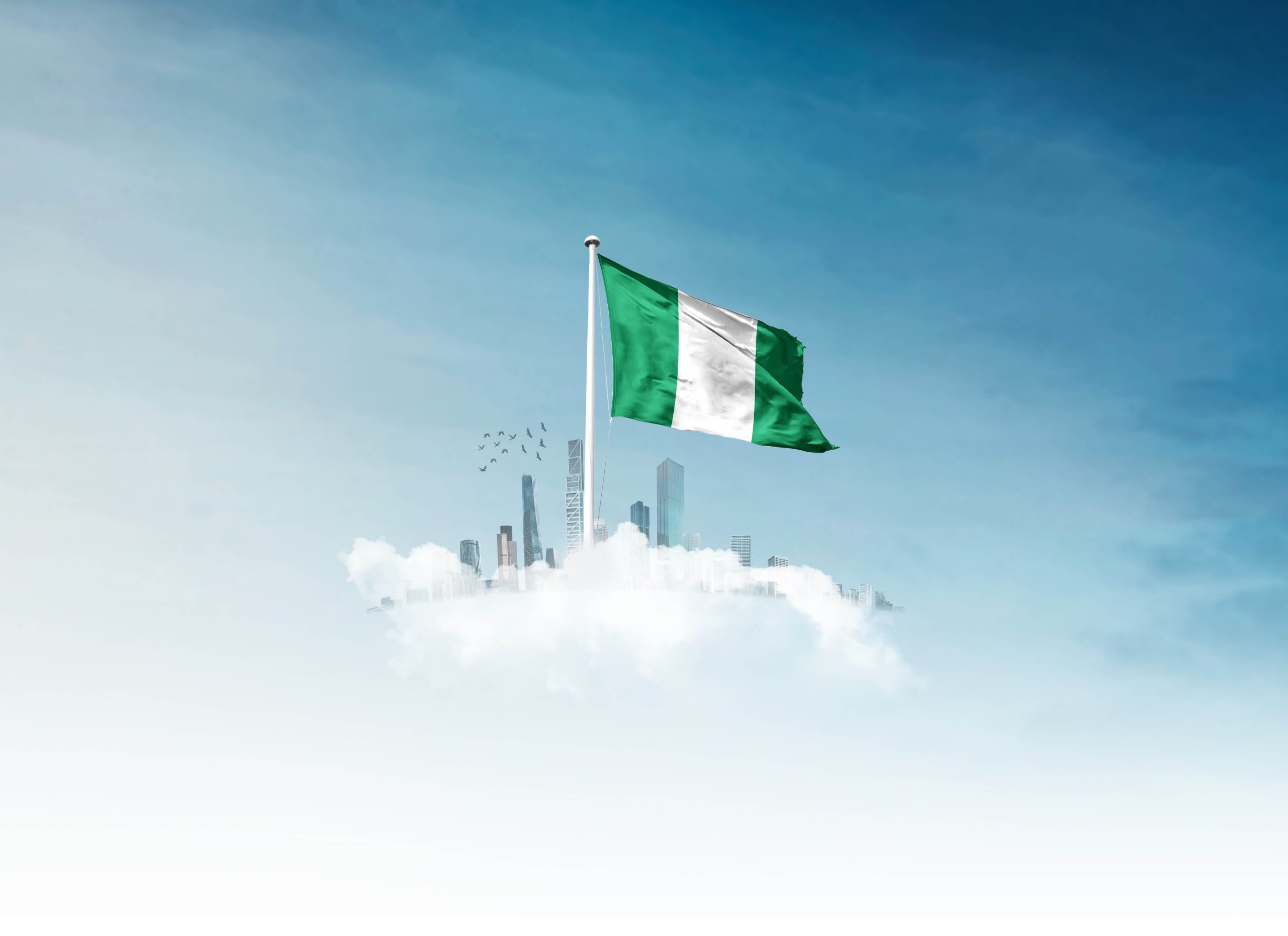 Nigerian flag on a tall pole waving in the sky above white clouds, with a modern city skyline faintly visible in the background and birds flying nearby.